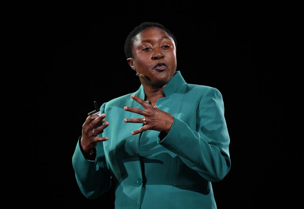 Woman in green jacket speaks onstage