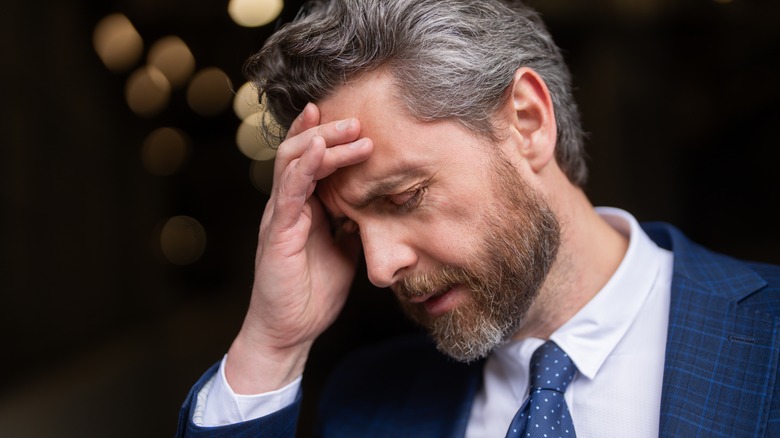 man holding his forehead with a headache